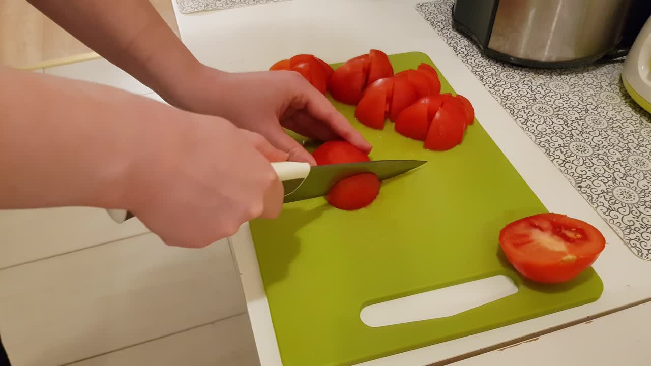 mujer caucásica cocinando y cortando tomates