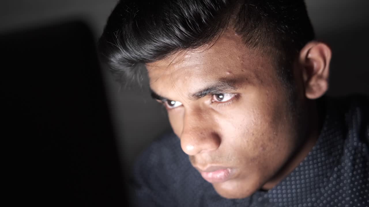 젊은 남자가 밤에 노트북에 집중하고 있습니다.