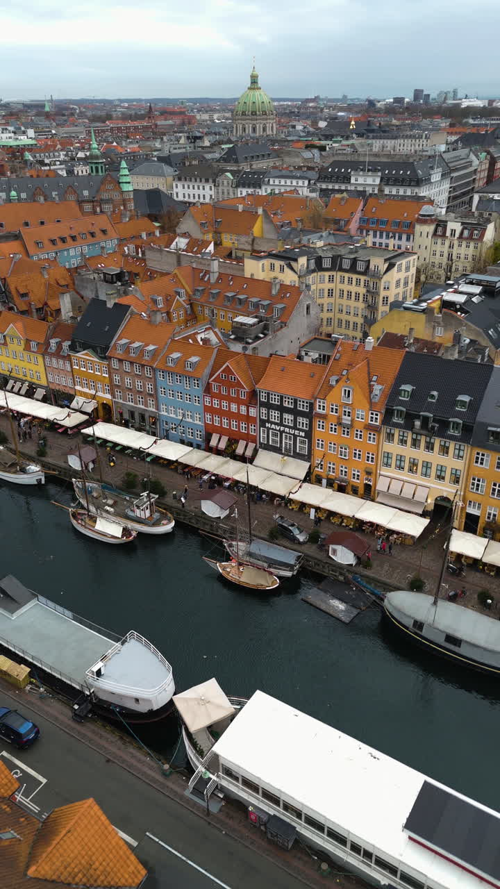 Lodret luftfoto af farverige bygninger og skibe ved havnefronten i København