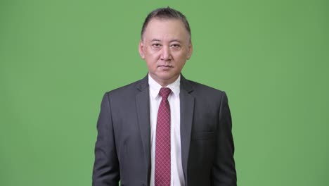 mature japanese businessman against green background