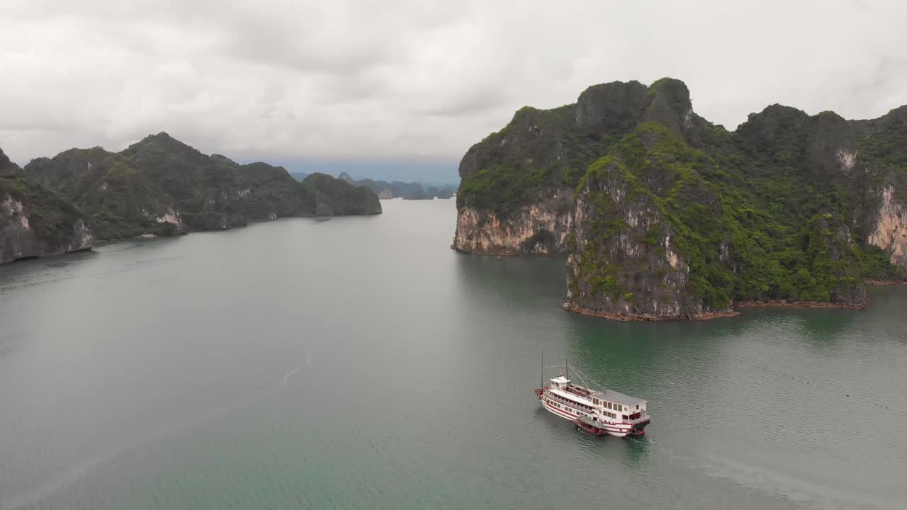 descripción completa del crucero que viaja a lo largo de la bahía de halong con horizonte nublado