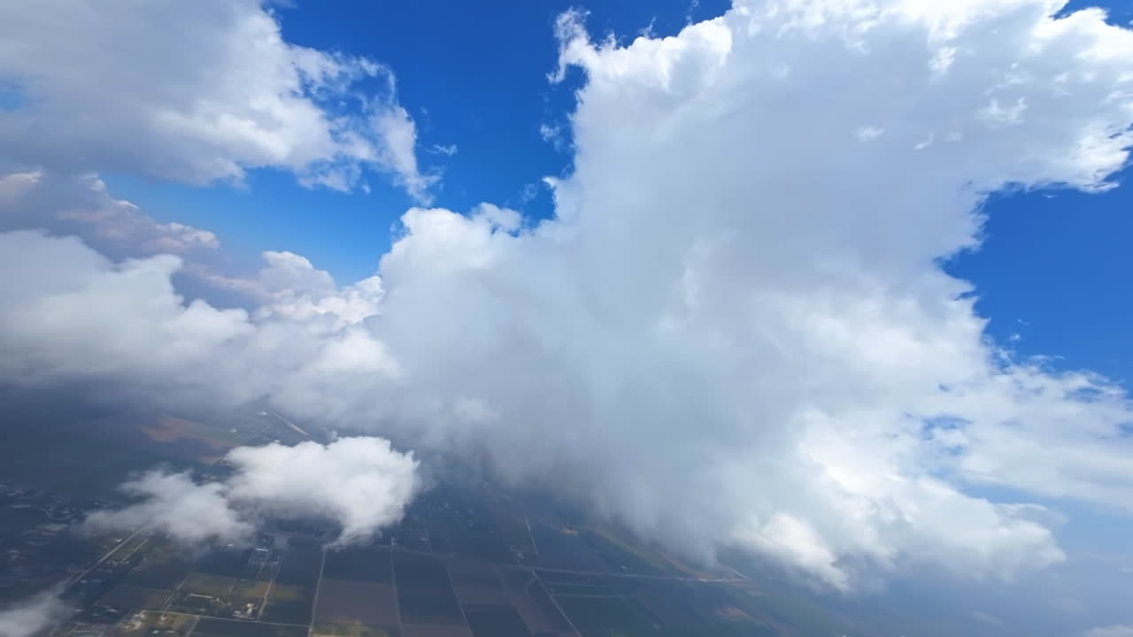 Panning footage inside the white cloudscape. Urban landscape is seen through the clouds below. FPV drone.