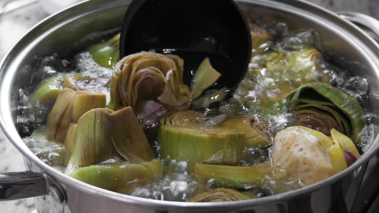 Boiling and cooking artichokes in saucepan, closeup
