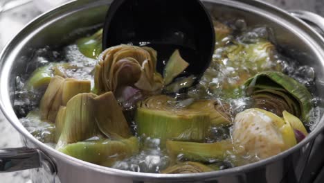 boiling and cooking artichokes in saucepan, closeup