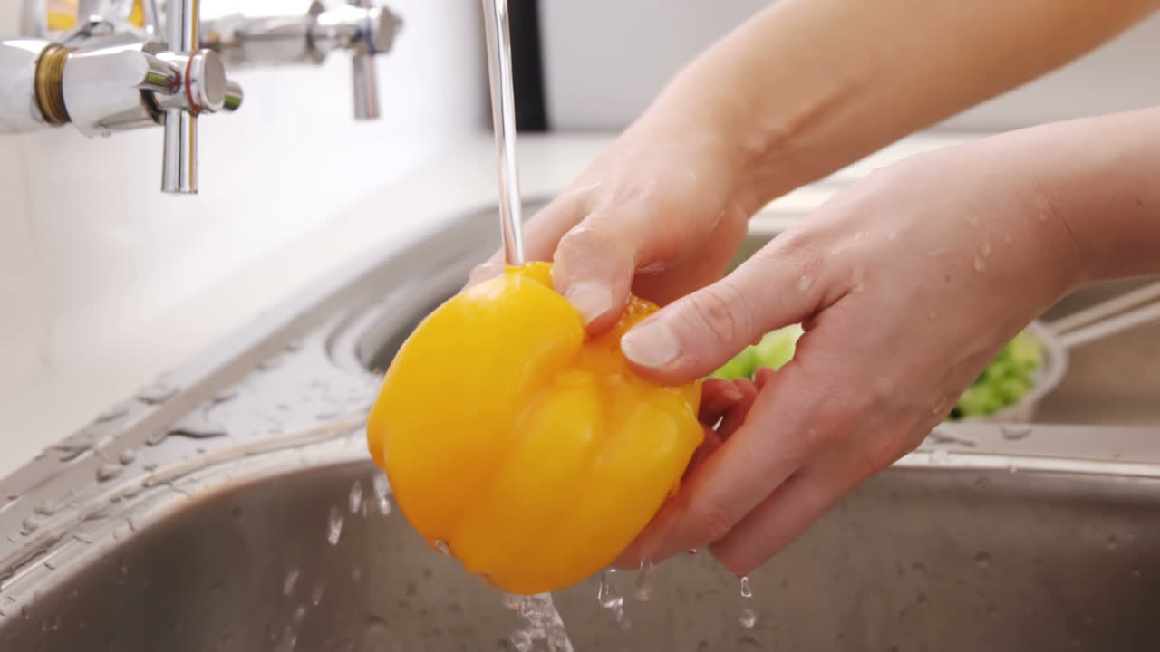 Primer plano de una mujer lavando pimiento morrón