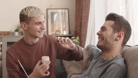 man applying clay mask on face of his boyfriend