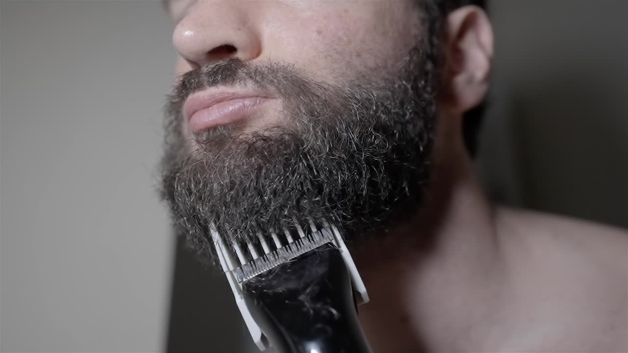 Man Trimming Thick Beard with Electric Razor, Close-Up
