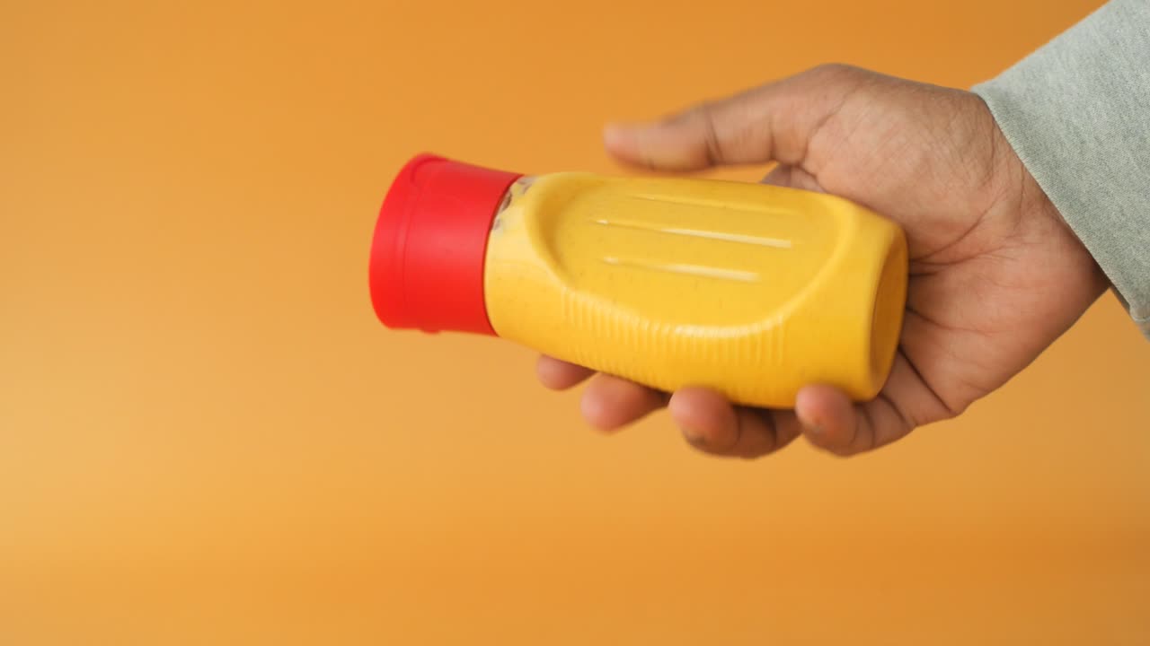 persona que sostiene una botella de mostaza