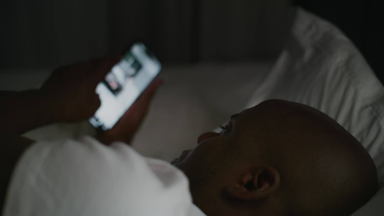 밤에 침대에 드폰을 사용하는 남자