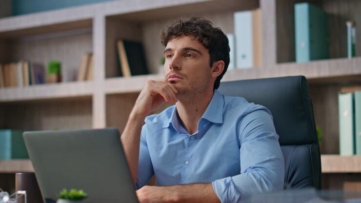 Uomo d'affari pensieroso che contempla una soluzione seduto alla scrivania. Professionista.