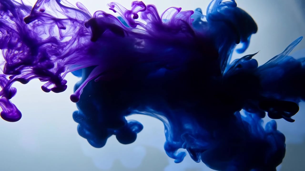 Movimento ravvicinato di pennacchi di inchiostro viola e blu che si fondono in acqua limpida, con nastri filamentosi, dense nuvole arrotondate, sottili viticci, una diffusione delicata e un contrasto di colori luminoso sotto una luce soffusa.