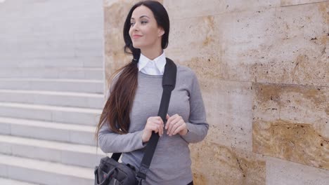 Grinning-woman-in-sweater-near-wall-looking-over