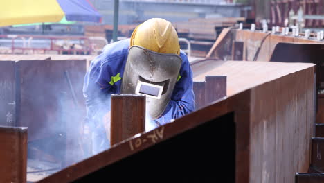 welder wears welding mask while fabricating steel structure