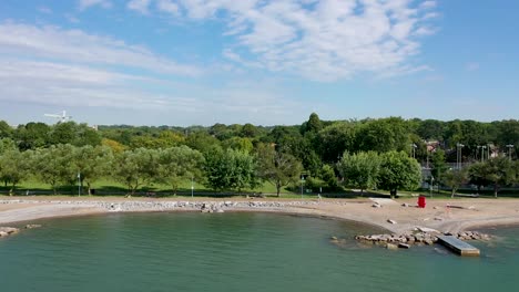 Toma-Aérea-Volando-A-Lo-Largo-De-La-Costa-De-Un-Día-Soleado-De-Verano-En-El-Lago-Ontario-A-Las-Afueras-De-Toronto