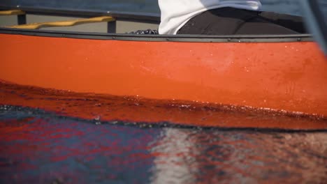 two young men paddle through lake water close up in a red canoe in the autumn season