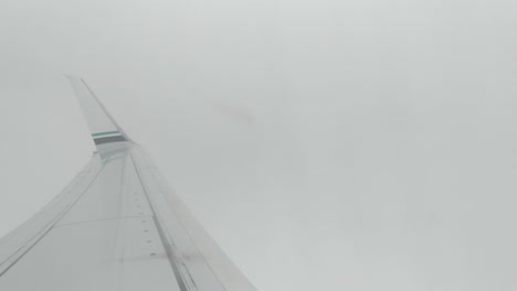 mirando el avión por encima del ala mientras el avión gana altitud y pasa a través de las nubes