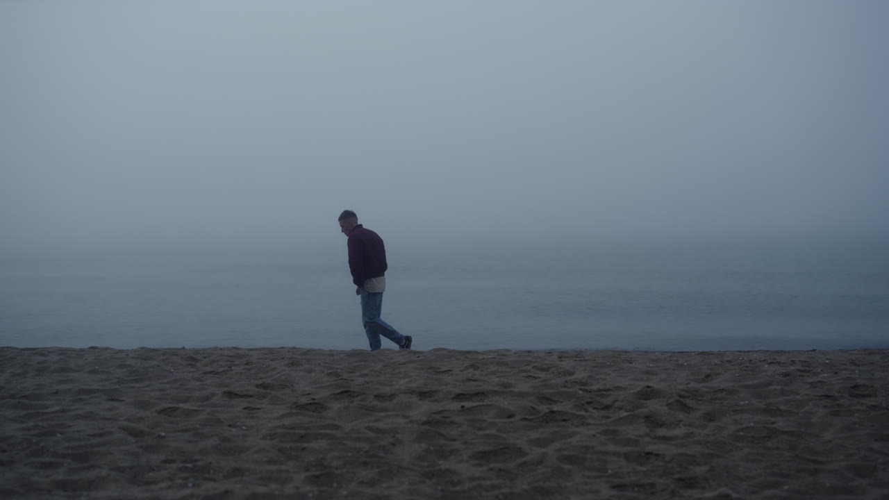 hombre de ensueño buscando vista al mar en la mañana brumosa. hombre molesto de pie en la playa de arena