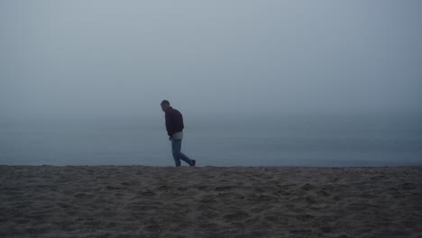 dreamy guy looking sea view in foggy morning. upset man standing on sandy beach