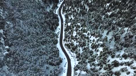 aerial view over an icy road on a snowed mountain during a cold winter afternoon