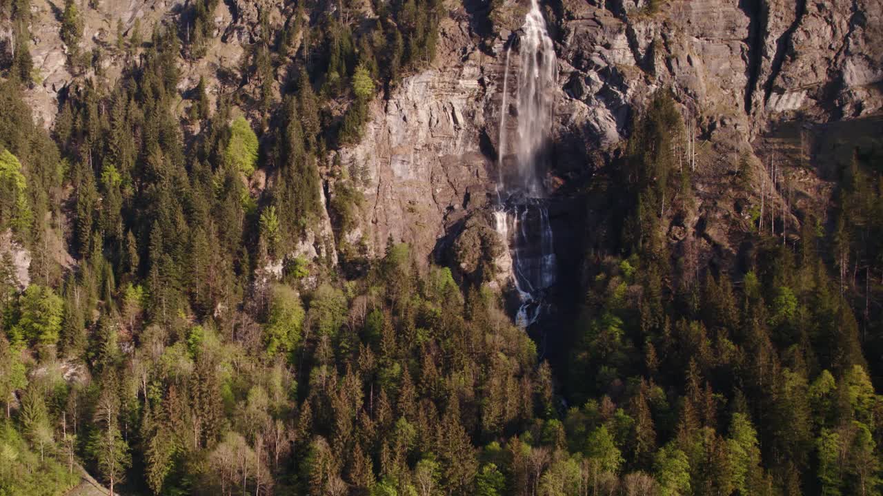 Aerial drone footage raising up from a distance with stunning views of Fallbach, a stunning waterfall in Grindelwald, Switzerland