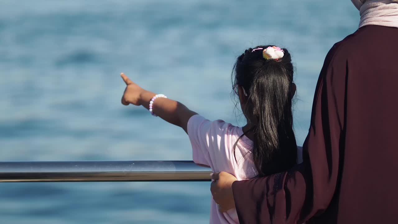 A girl pointing at the sea with her family