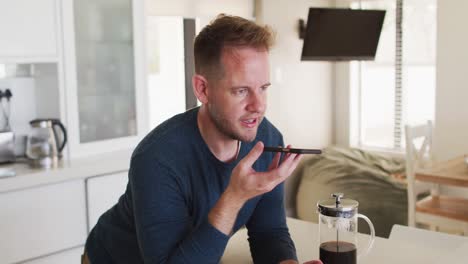 Caucasian-man-talking-on-a-smartphone-in-kitchen