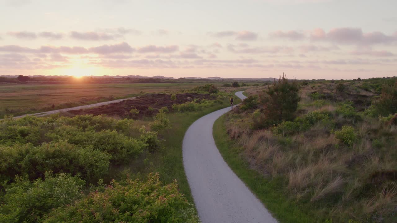Fredfyldt solnedgang over grussti og cyklist, Terschelling, Friesland