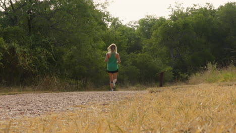 a slow-motion shot captures a woman sprinting on a forest trail, emphasizing her energy and the vibrant greenery surrounding her as she enjoys the thrill of running in nature.