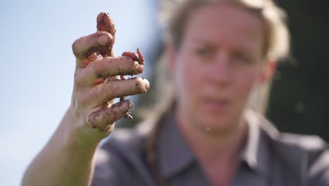 woman farmer holding one worm in hand, vermicompost farming outdoor