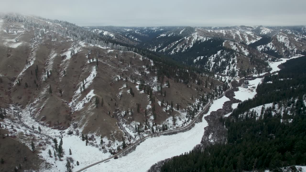 Cold and Snowy Winter Canyon with snow and road running through- aerial