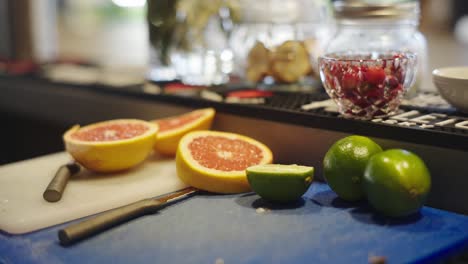 cut-up oranges and limes, with a bowl of raspberries in the back, handheld shot