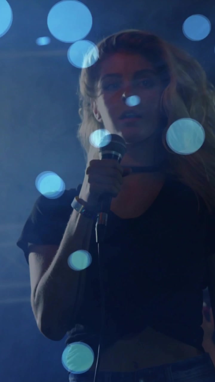 Vertical video: Hand gripping mic starting blue orbs as singer in rehearsal tilting cam moving