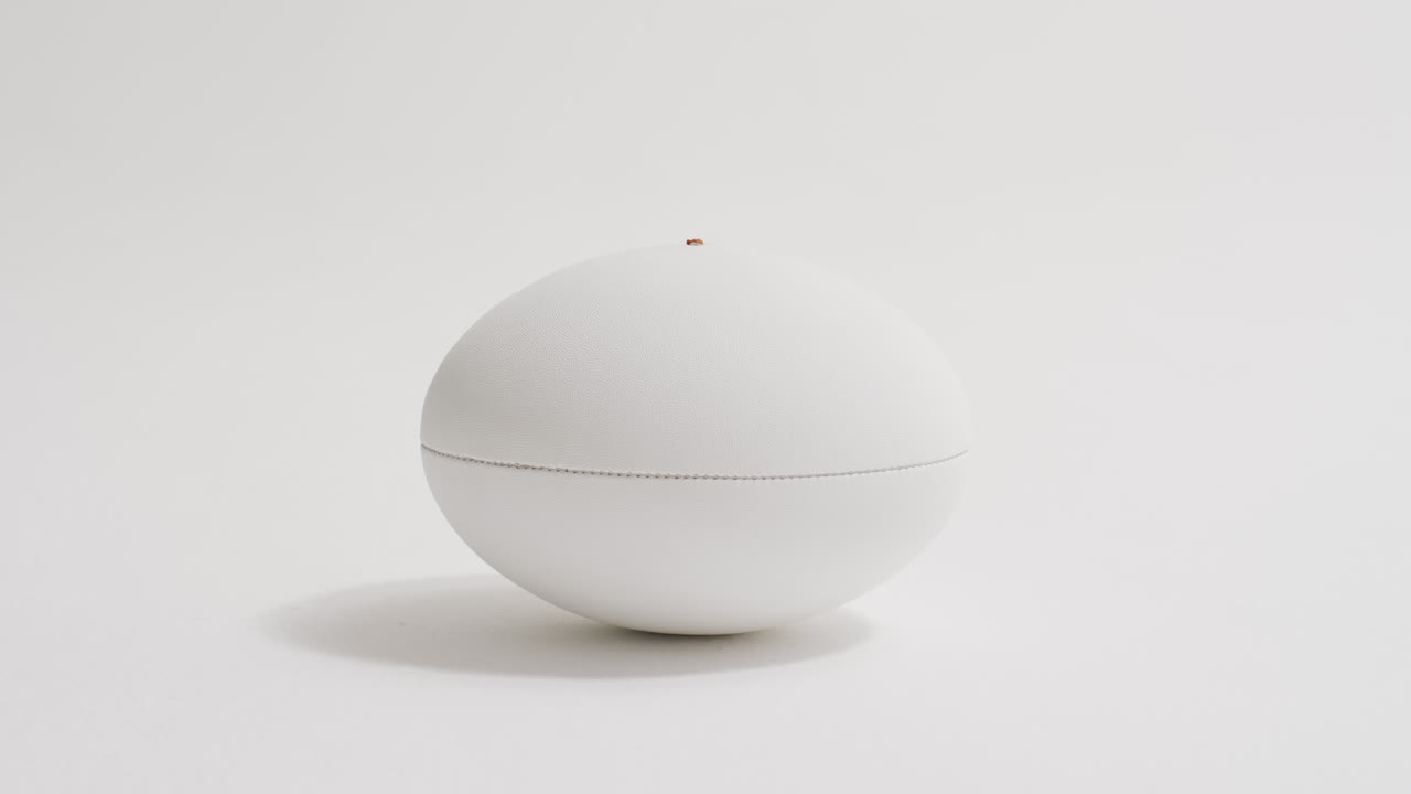 Vit rugbyboll på vit bakgrund med utrymme för text, i slow motion