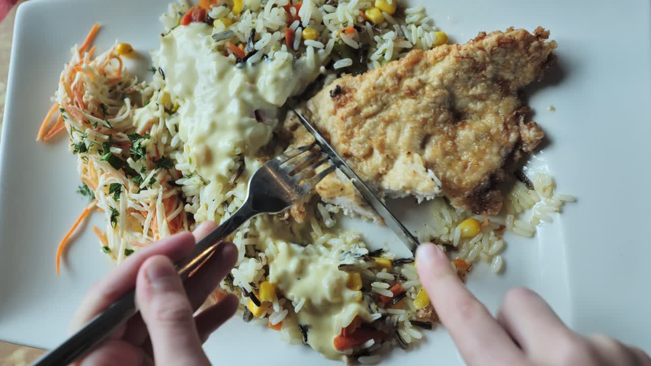 Close-up of a kid enjoying a delicious chicken meal with rice, sauce, and salad