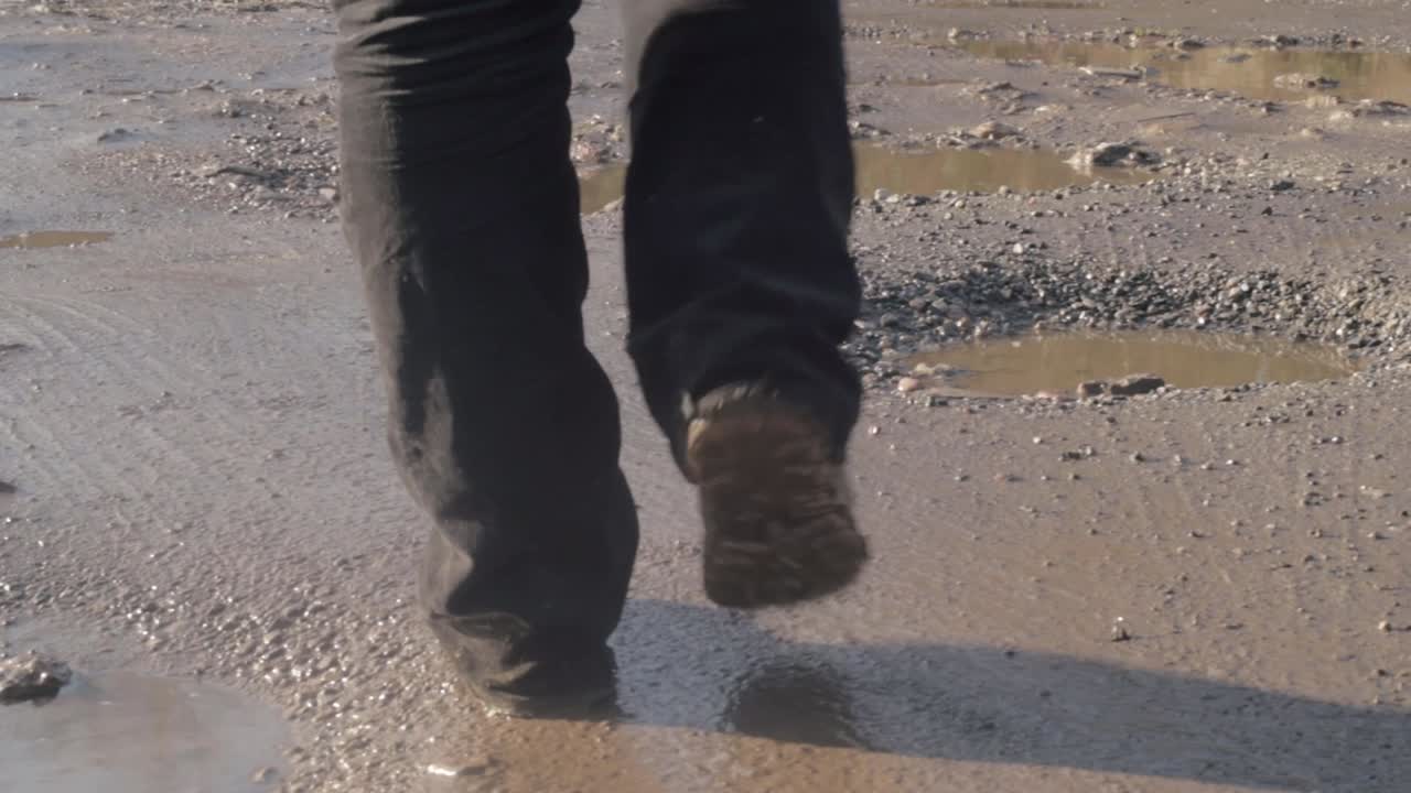 도로의 진흙탕 움푹 들어간 곳을 가로질러 걷는 발