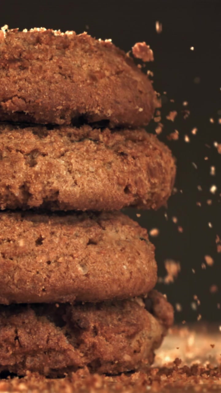Close-up of Crumbs Falling on Stacked Brown Cookies