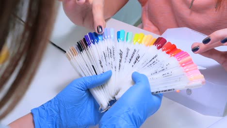 nail technician shows the color palette of nail services in beauty salon.