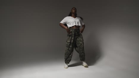 Full-Length-Studio-Portrait-Shot-Of-Young-Woman-Dancing-With-Low-Key-Lighting-Against-Grey-Background