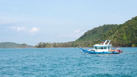 a boat travels across clear blue waters near lush green hills in phuket, thailand, under bright daylight