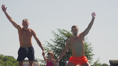 multi-generation family on summer holiday jumping into swimming pool