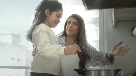 little girl learning cooking with mom at home