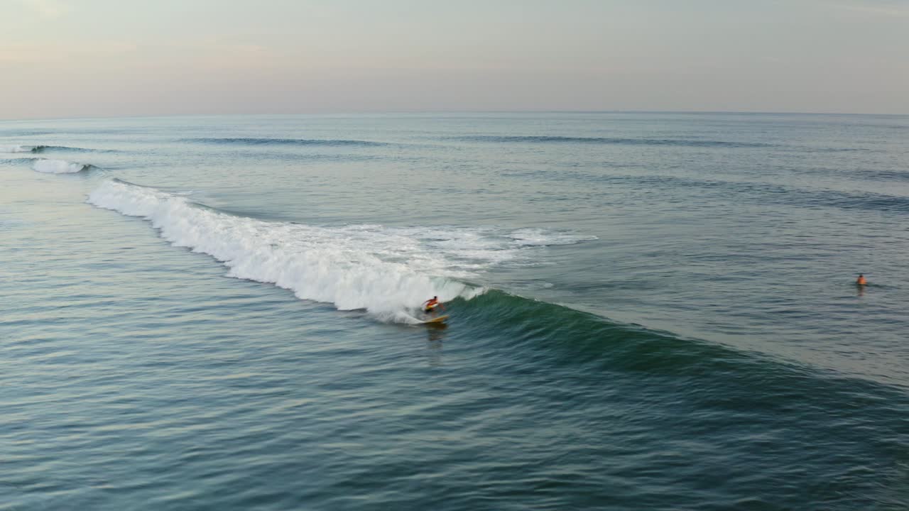 hermoso destino de surf, surfistas montando olas al atardecer en la playa tropical