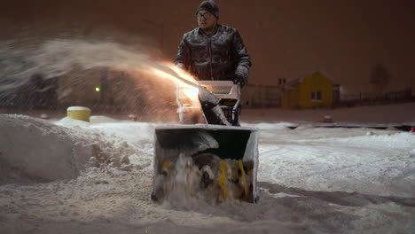 man using snowblower at night