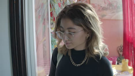 young chinese lady wearing black top, gold necklace, and eyeglasses going out