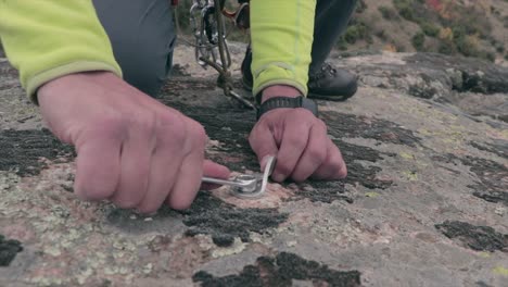 rock climber screwing a screw on a rock preparing it for climbing