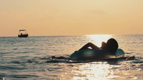 boy jumping on rubber ring at sea. child swimming in sea at evening