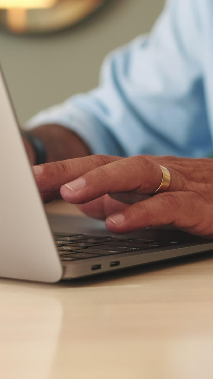Close-up of Man's Hands Typing on Laptop Keyboard