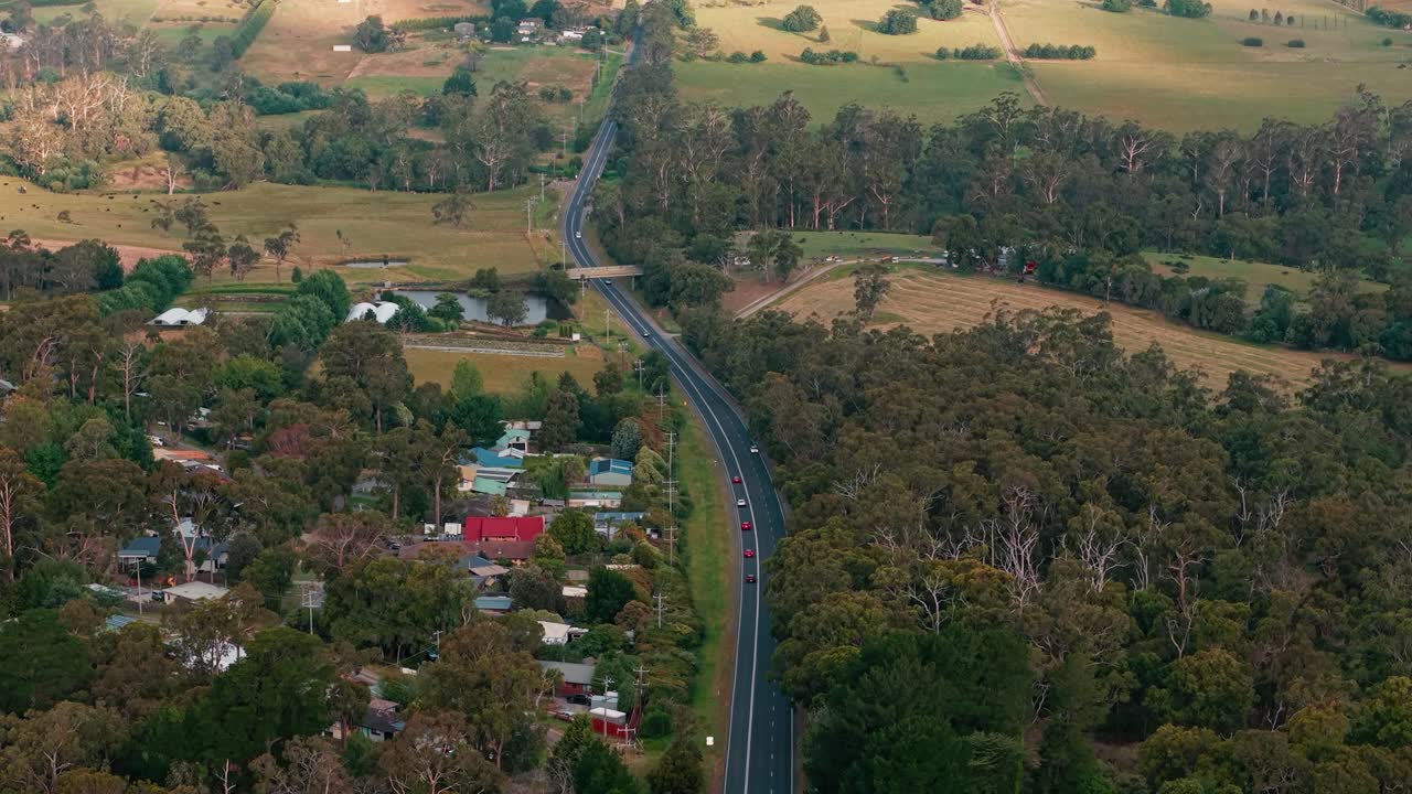 Breathtaking aerial footage of Seville's lush countryside near Melbourne, Australia, showcasing winding roads, expansive forest, and charming rural landscapes in serene daylight