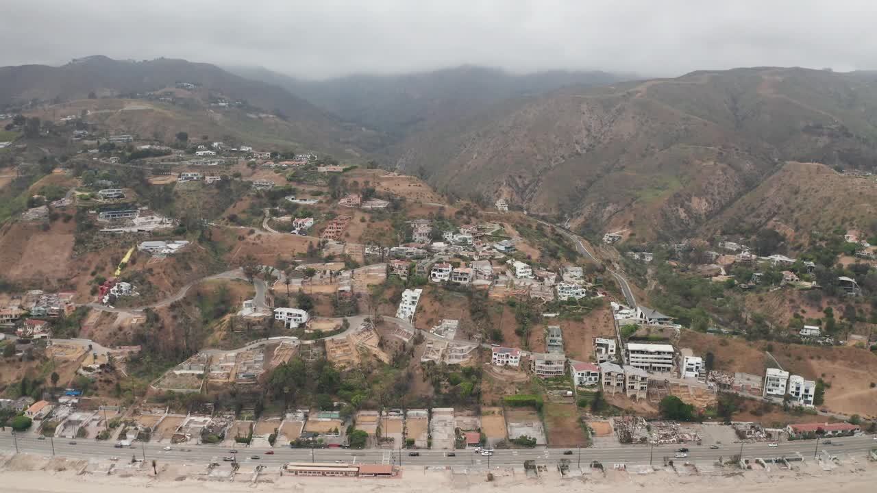 Wide push-in aerial shot of homes in the upscale ocean view neighborhood of Las Flores after the Palisades Fire in Malibu, California. 4K at 30 FPS