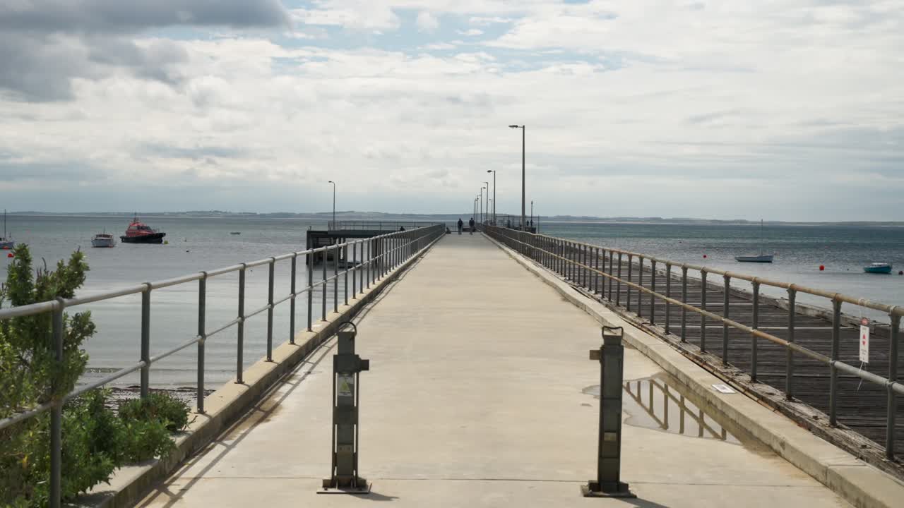 Clouds drift across the sky above a scenic pier, creating a peaceful and dynamic coastal atmosphere.